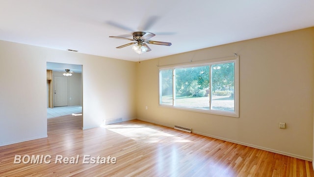 empty room featuring ceiling fan, a baseboard heating unit, and light wood-type flooring