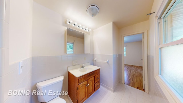 bathroom with vanity, tile walls, and toilet