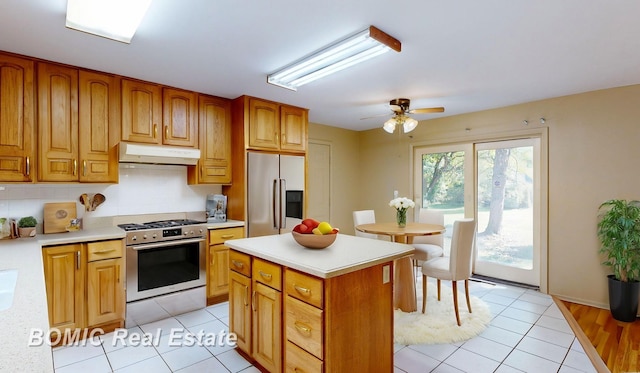 kitchen with a center island, backsplash, ceiling fan, light tile patterned flooring, and stainless steel appliances