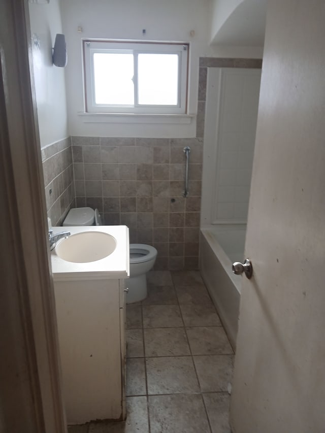 bathroom with toilet, vanity, tile walls, tile patterned flooring, and a bathing tub