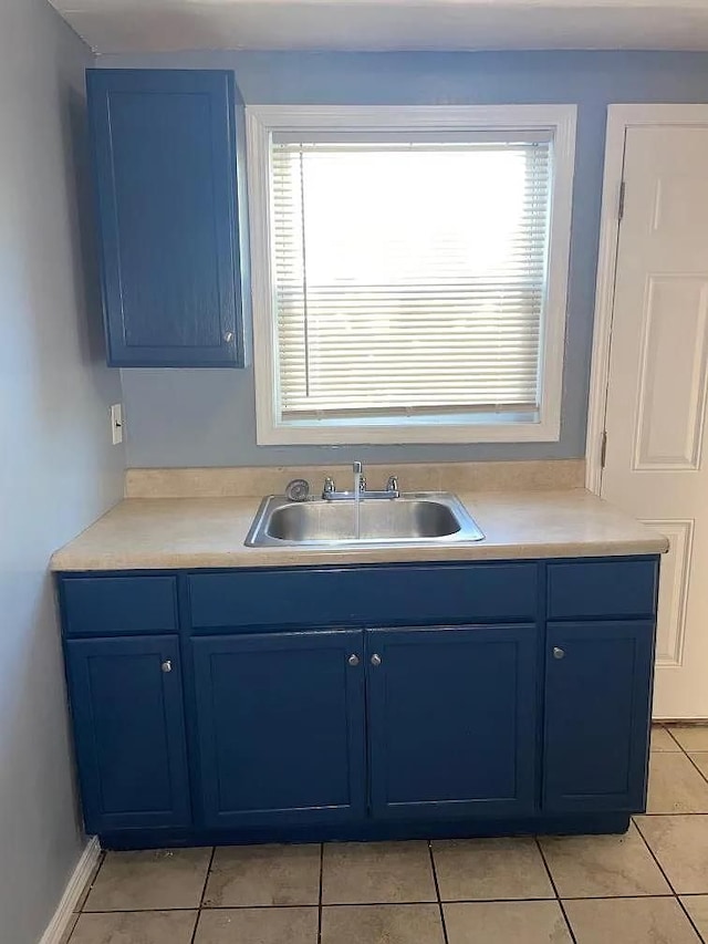 kitchen with light tile patterned floors, blue cabinets, and sink