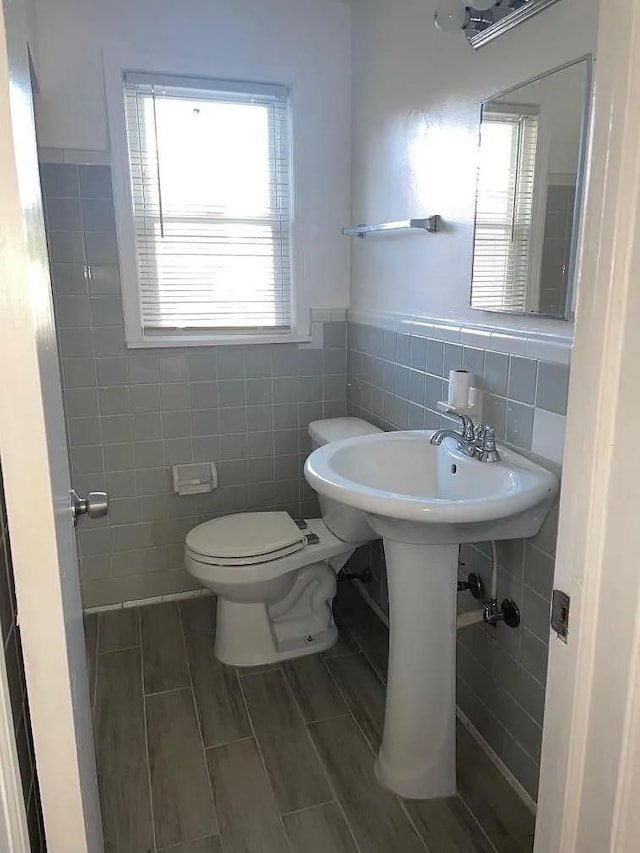 bathroom featuring toilet and tile walls