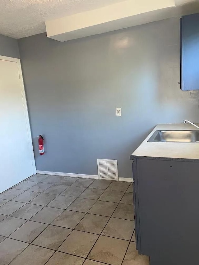 clothes washing area featuring a textured ceiling, tile patterned floors, and sink