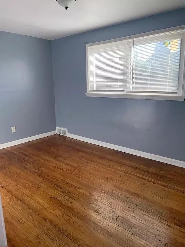 unfurnished room with dark wood-type flooring