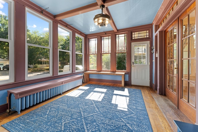 unfurnished sunroom with radiator heating unit and beam ceiling