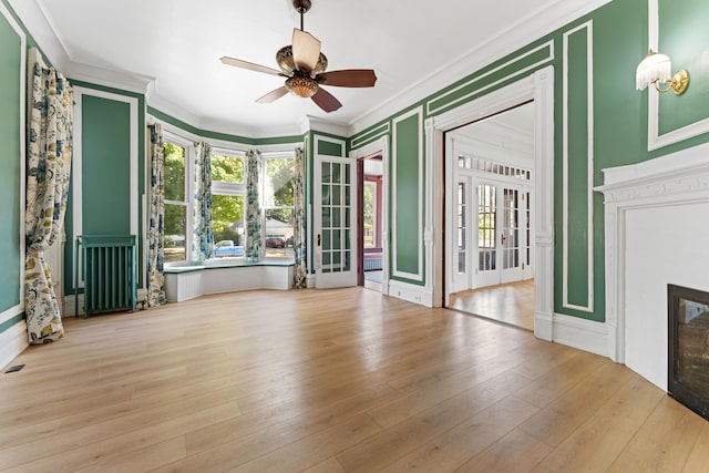 unfurnished living room with ceiling fan, light wood-type flooring, ornamental molding, and french doors