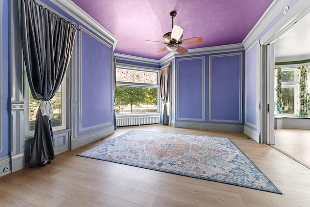 interior space featuring ceiling fan, light wood-type flooring, ornamental molding, and radiator