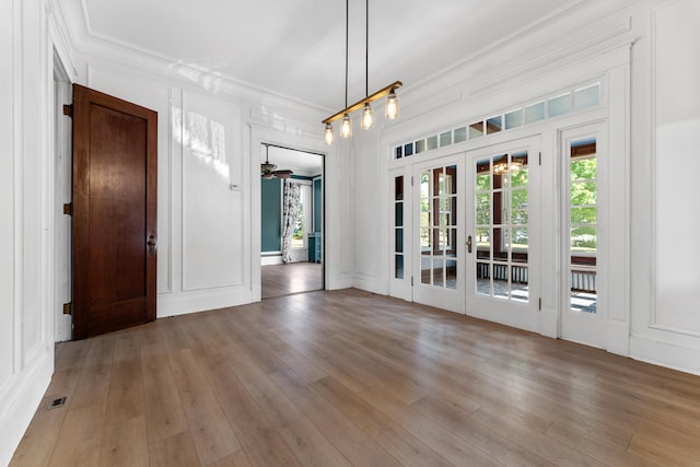 unfurnished dining area with french doors, hardwood / wood-style flooring, ceiling fan, and crown molding