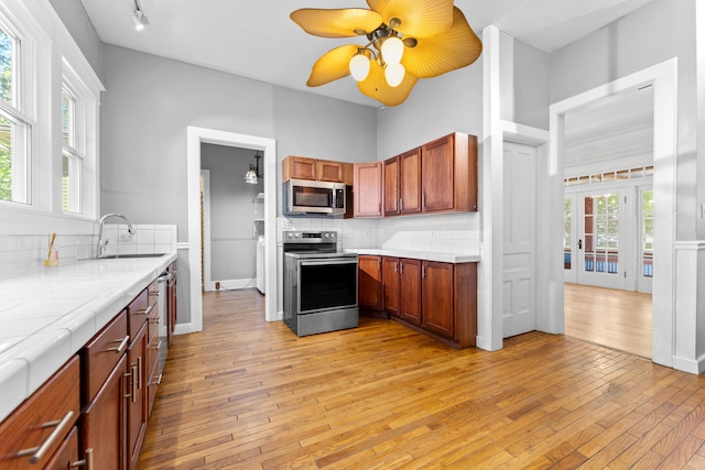 kitchen featuring appliances with stainless steel finishes, tasteful backsplash, light hardwood / wood-style flooring, and sink