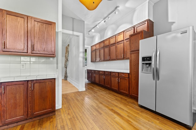 kitchen with decorative backsplash, stainless steel fridge, light hardwood / wood-style flooring, and track lighting