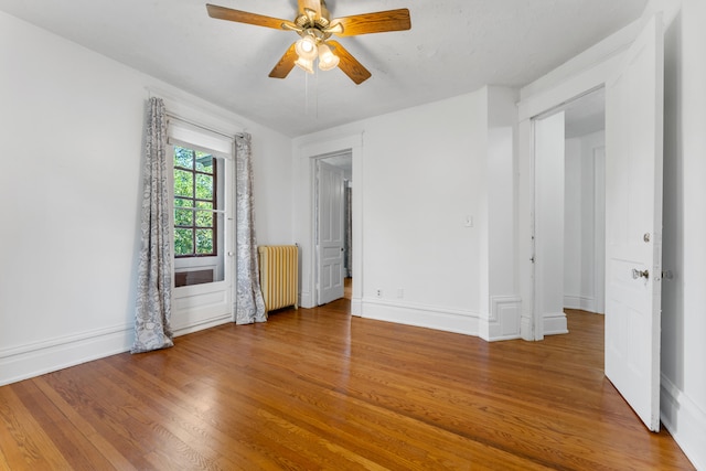 spare room with hardwood / wood-style floors, radiator, and ceiling fan