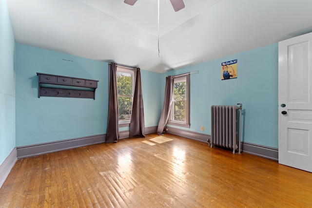 unfurnished room with hardwood / wood-style floors, ceiling fan, radiator heating unit, and baseboard heating