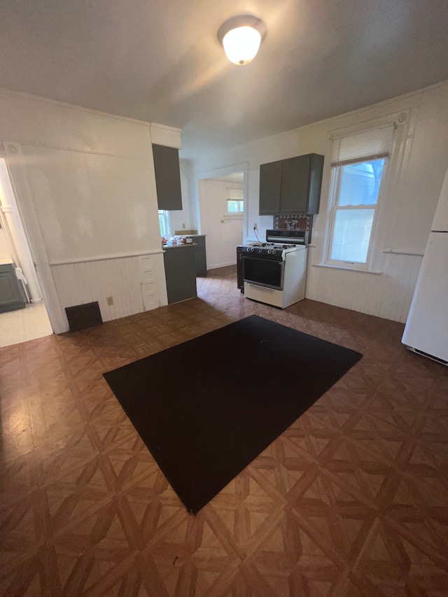 interior space featuring parquet floors, a wealth of natural light, and white range with gas cooktop