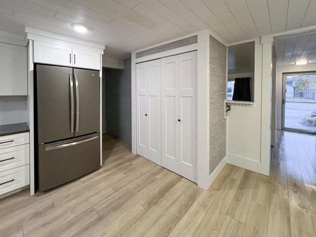 120 N Cedar St, Traverse City, MI 49684 - kitchen with freestanding refrigerator, white cabinetry, wooden ceiling, light wood-type flooring, and dark countertops