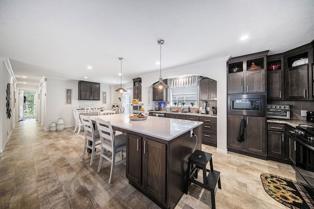 kitchen featuring dark brown cabinets, sink, hanging light fixtures, a center island, and stainless steel microwave