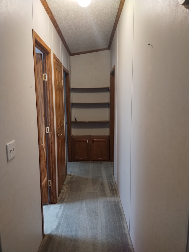 corridor featuring dark carpet, ornamental molding, and a textured ceiling