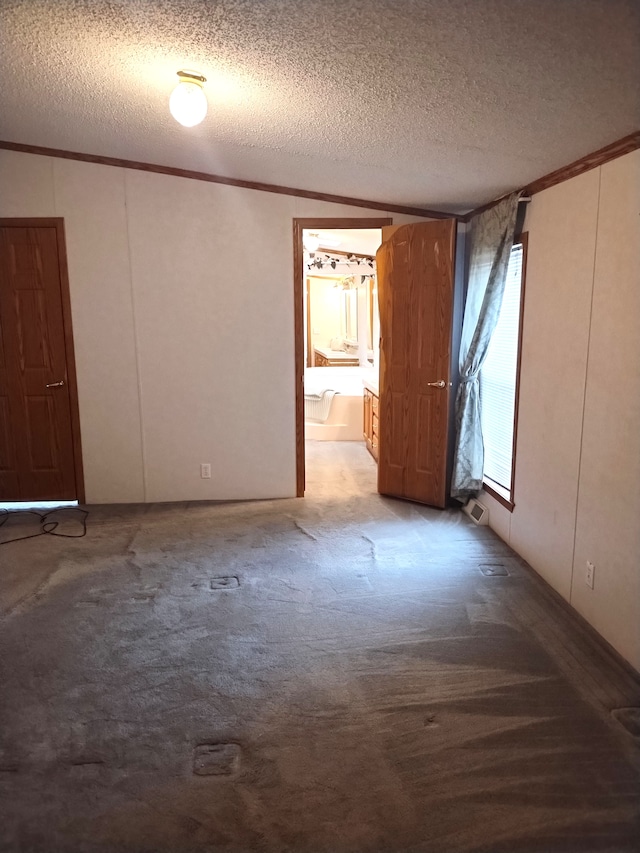 spare room featuring a textured ceiling, carpet floors, and crown molding