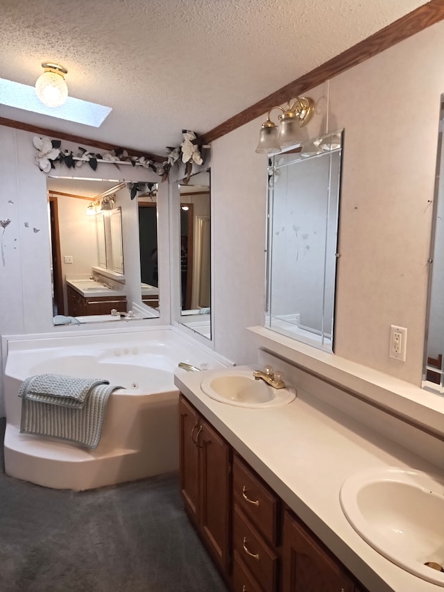 bathroom with a skylight, a textured ceiling, a bathtub, vanity, and ornamental molding