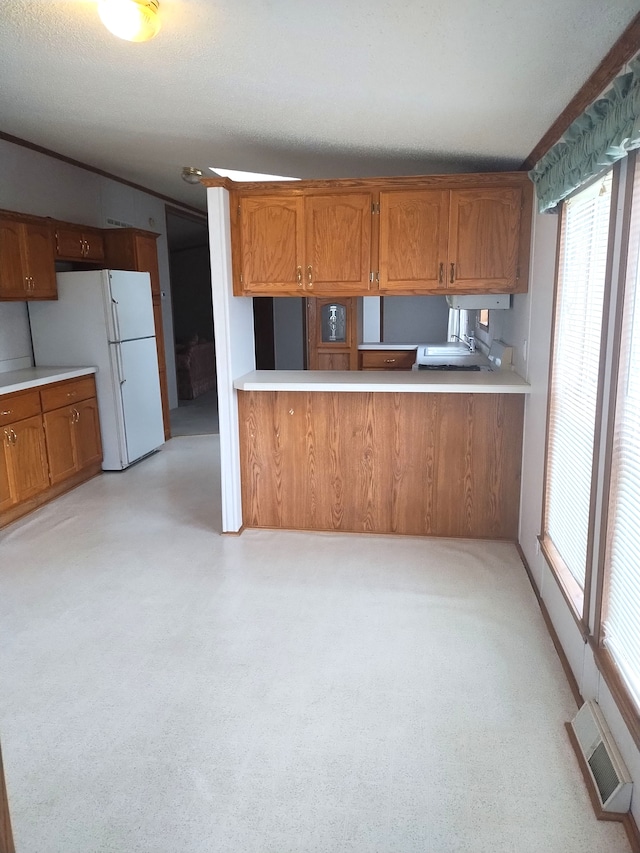 kitchen with kitchen peninsula, a textured ceiling, and white refrigerator