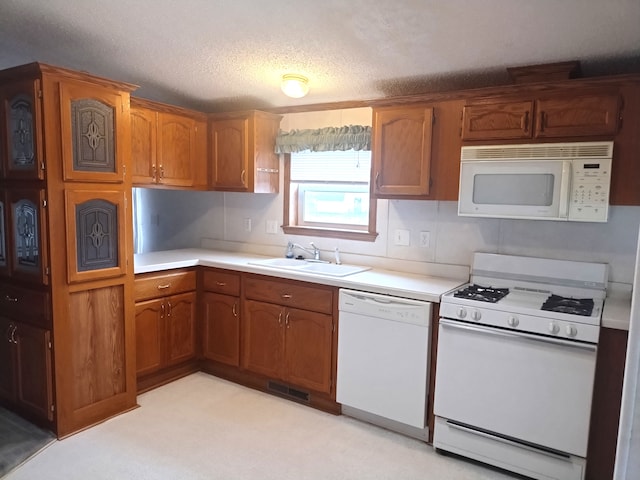 kitchen with a textured ceiling, white appliances, sink, and light carpet