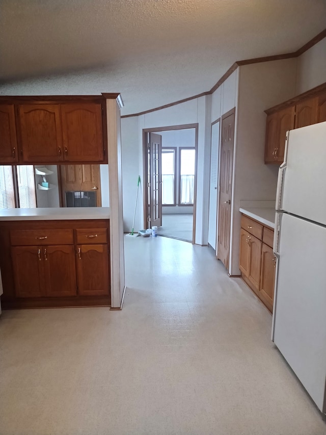 kitchen with white fridge, ornamental molding, a textured ceiling, and vaulted ceiling