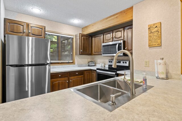 5830 Shanty Creek Rd, Bellaire, MI 49615 - kitchen featuring stainless steel appliances, a textured ceiling, light countertops, and a sink