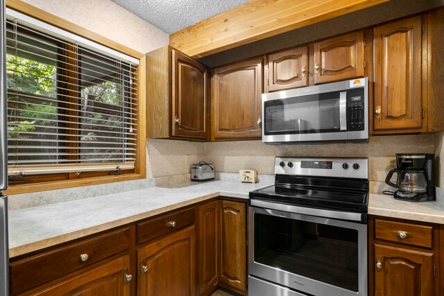 5830 Shanty Creek Rd, Bellaire, MI 49615 - kitchen with appliances with stainless steel finishes, light countertops, decorative backsplash, and a textured ceiling
