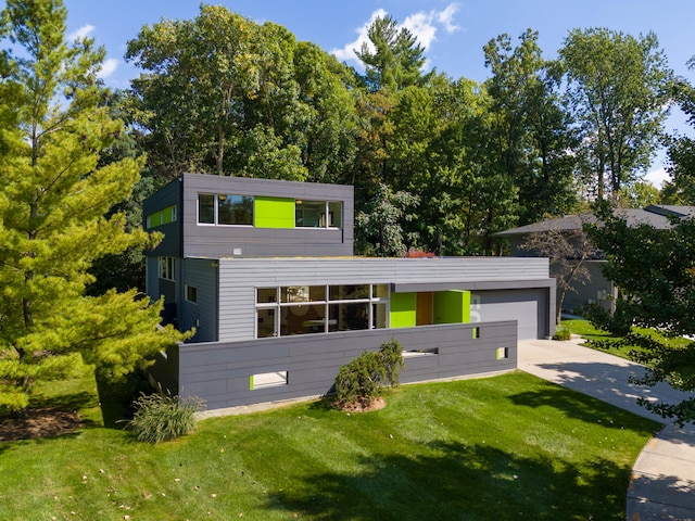 contemporary home with driveway, an attached garage, and a front lawn