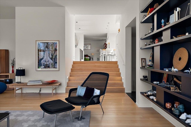 living area with stairway, built in shelves, baseboards, and wood finished floors