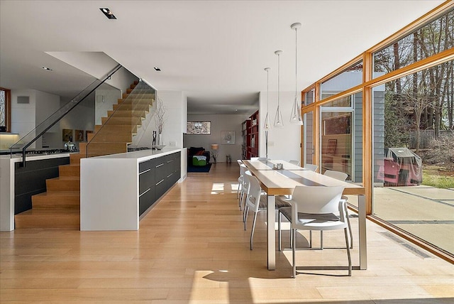 dining area with a wall of windows, stairway, light wood-style floors, and visible vents