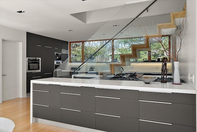 kitchen with light wood-type flooring, modern cabinets, gray cabinets, and oven