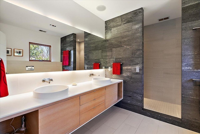 bathroom featuring visible vents, a walk in shower, double vanity, tile walls, and a sink