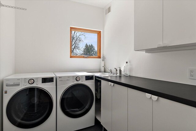laundry room featuring a sink, visible vents, cabinet space, and washer and clothes dryer