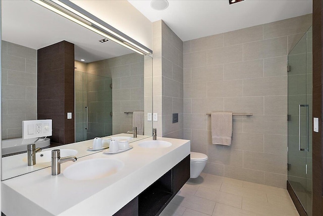 bathroom featuring tile patterned flooring, toilet, a stall shower, tile walls, and a sink