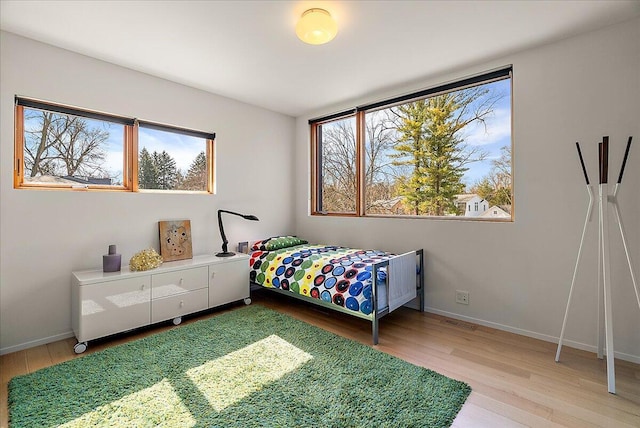 bedroom with visible vents, baseboards, and light wood finished floors