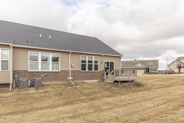 rear view of house featuring cooling unit, a wooden deck, and a lawn