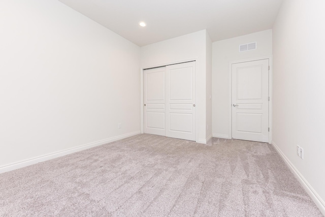 unfurnished bedroom with light carpet and a closet