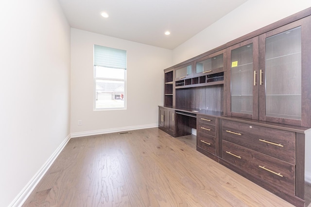 unfurnished office featuring built in desk and light wood-type flooring