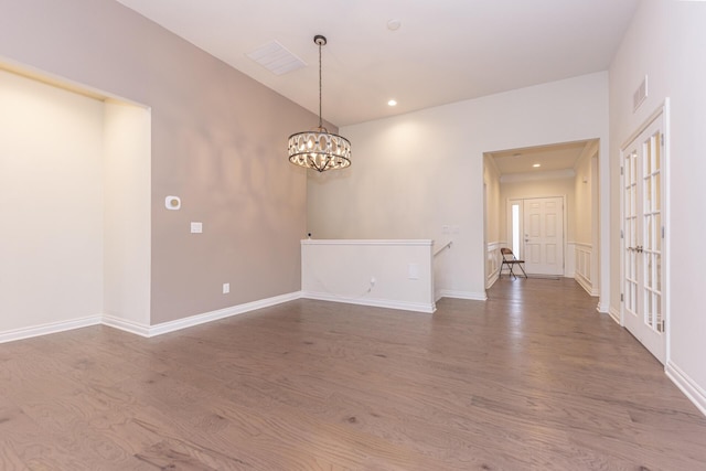 empty room featuring an inviting chandelier and hardwood / wood-style flooring