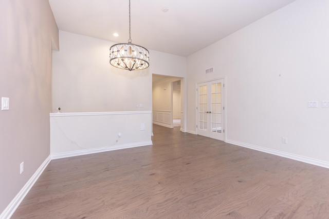 unfurnished room featuring french doors, dark hardwood / wood-style floors, and a notable chandelier