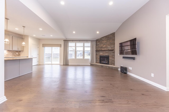 unfurnished living room with vaulted ceiling, a fireplace, and hardwood / wood-style floors