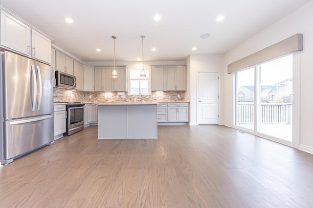 kitchen featuring gray cabinets, pendant lighting, backsplash, a center island, and stainless steel appliances