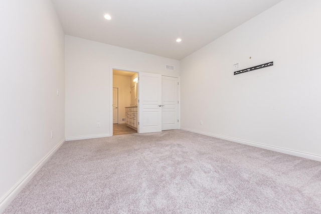 unfurnished bedroom with connected bathroom and light colored carpet