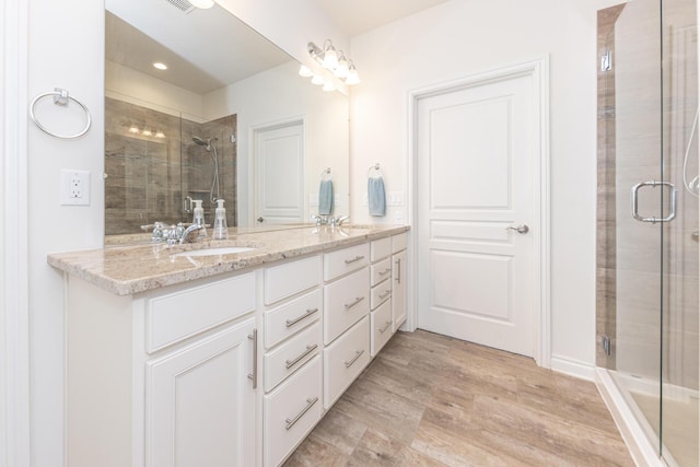 bathroom featuring a shower with door and vanity