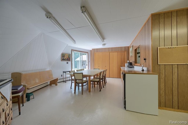 dining area featuring a baseboard radiator and wood walls