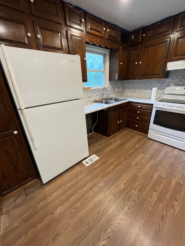 kitchen featuring decorative backsplash, sink, white appliances, and hardwood / wood-style flooring