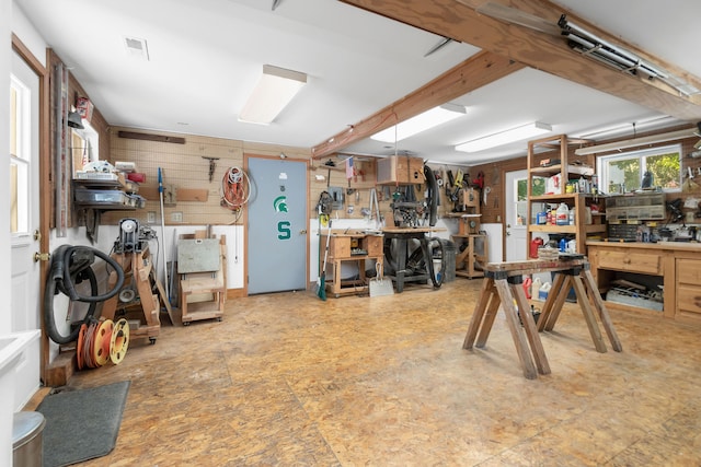 misc room with a workshop area and wood walls