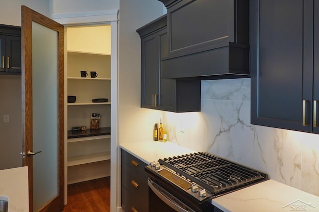 kitchen featuring premium range hood, decorative backsplash, dark hardwood / wood-style flooring, stainless steel gas stove, and light stone countertops