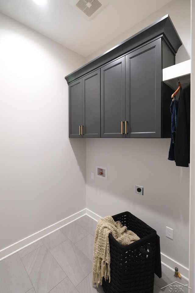 clothes washing area featuring cabinets, washer hookup, electric dryer hookup, and light tile patterned flooring