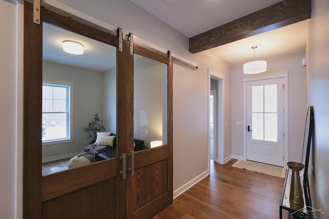 doorway to outside with dark hardwood / wood-style flooring, beam ceiling, and a barn door